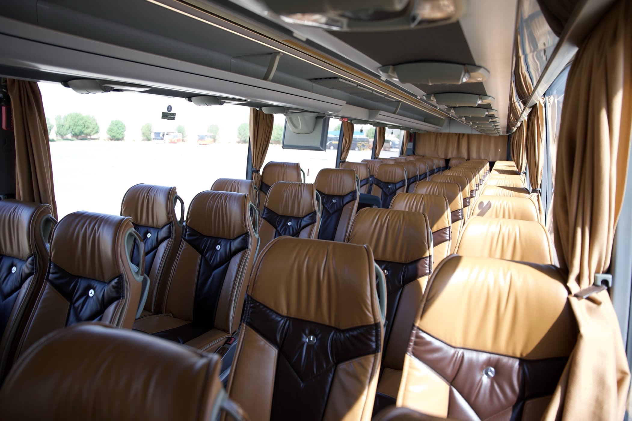 Rows of leather coach seats with curtains drawn back at the windows