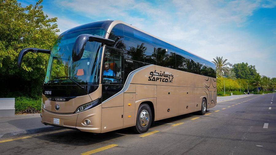A gold VVIP coach operated with SAT on a palm-lined road